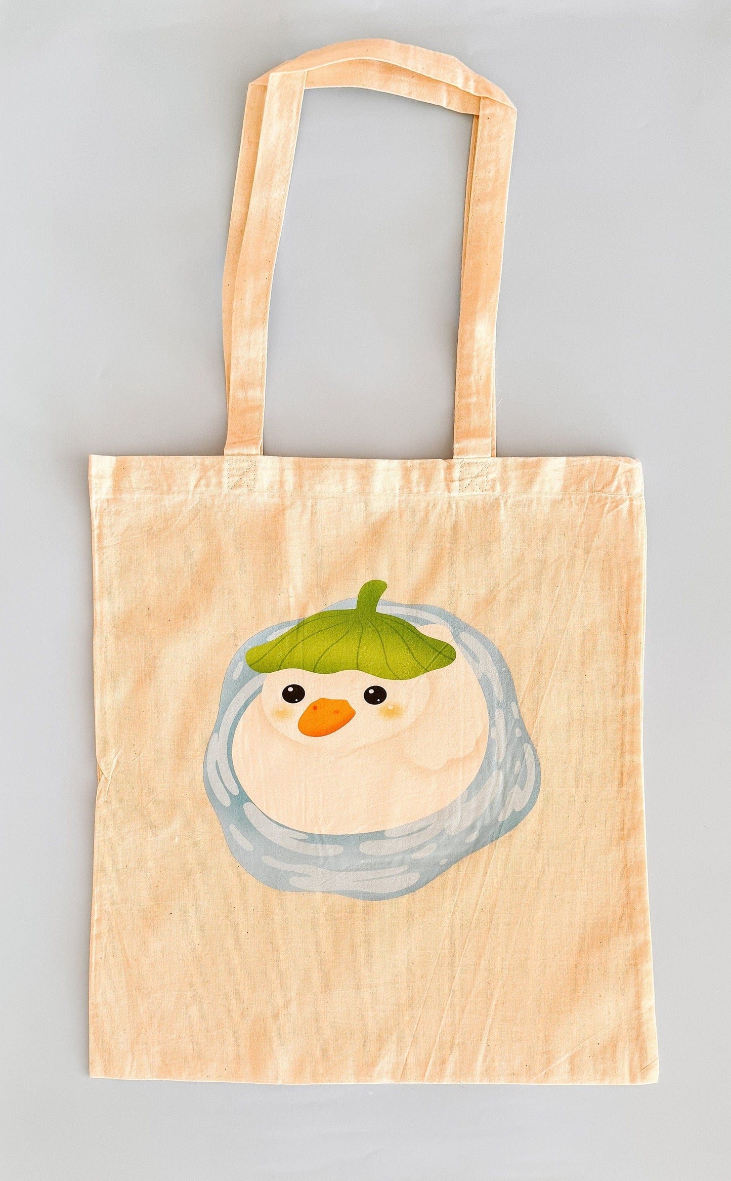 Adorable Kawaii duck sitting in a puddle tote bag. 100% cotton. Measures 42cm x 38cm wide.